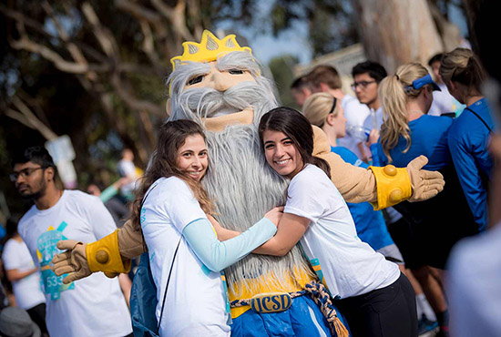 Two UCSD students stand on either side of the King Triton mascot